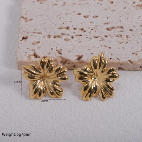 Par de aretes de flor dorada giratoria sobre topo, vistos de frente